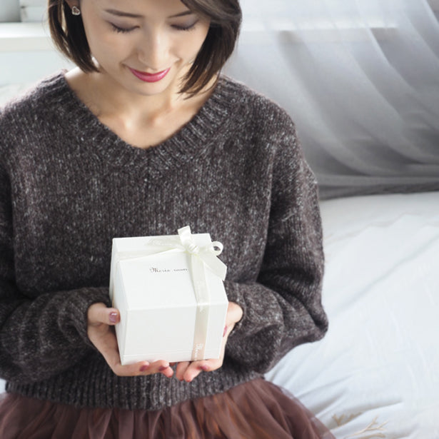 誕生日プレゼントとして世界にひとつの誕生石ローズを受け取った女性。オリジナル刺繍入りの白い一輪のバラが入ったギフトボックス。