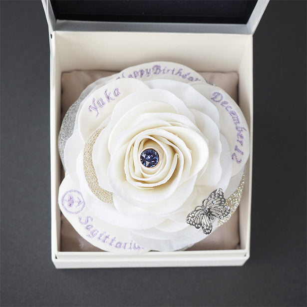 名前や愛のメッセージ、誕生日、星座が刺繍された白い一輪バラ。誕生石に合わせた刺繍糸で仕立てられた、世界にひとつだけの誕生石ローズギフト。
