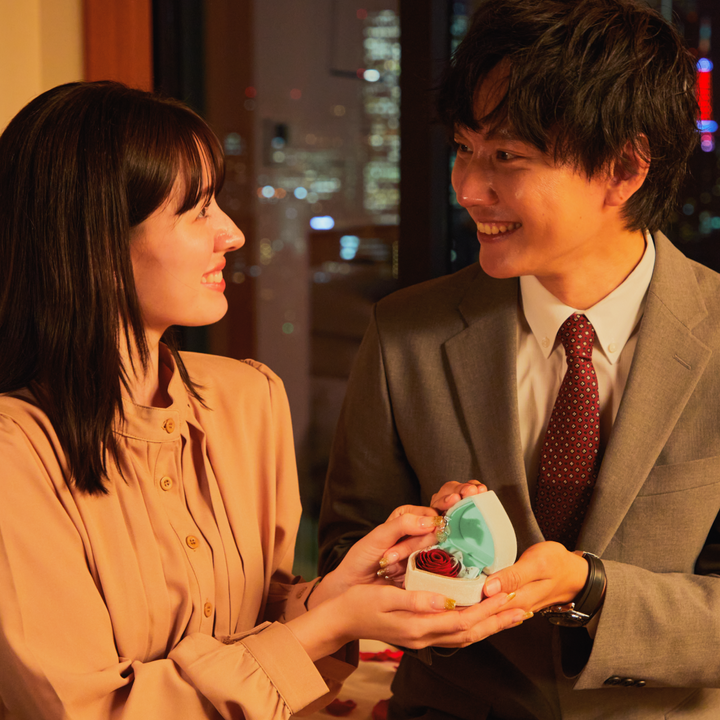 見つめ合うカップル。彼女の手を握り、プロポーズをする男性。彼女は幸せそうに見つめている。