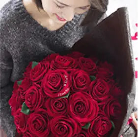 50本の赤バラ花束を抱きかかえる女性