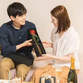 男性が部屋で女性にバラを渡す様子