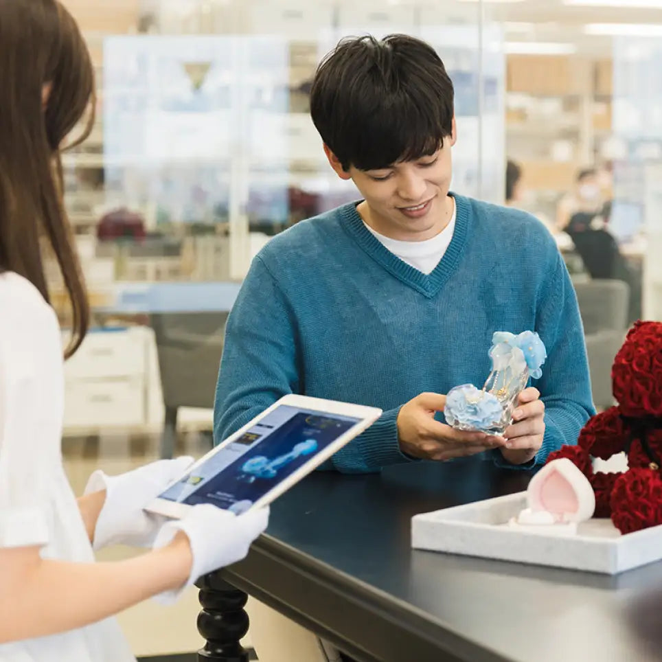 アートフラワーを選ぶ理由 ⓸特別な想いを、プロと一緒にカタチに。プロポーズに贈るフラワーギフトを選ぶ男性と、隣りでアドバイスするメリアルームのフラワーコンシェルジュ。