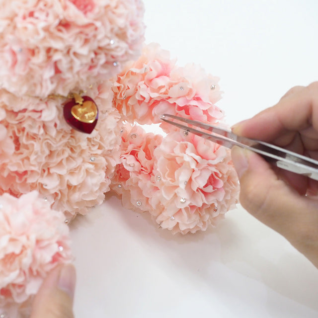 やさしいピンクとホワイトの桜の花を108輪使い、一輪ずつ丁寧にハンドメイドで仕立てられたフラワーベア。ふんわりとした色合いと繊細な手仕事が魅力。プロポーズや春に誕生日の贈り物にもぴったりなテディベア。