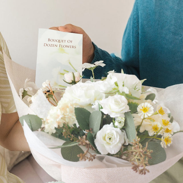 ホワイトダズンフラワーの花束に花言葉カードが付いている。12本の花に込められた想いをカードで伝えることができ、プロポーズや記念日にぴったり。説明なしでも気持ちが届く、特別な意味を持つフラワーブーケ。
