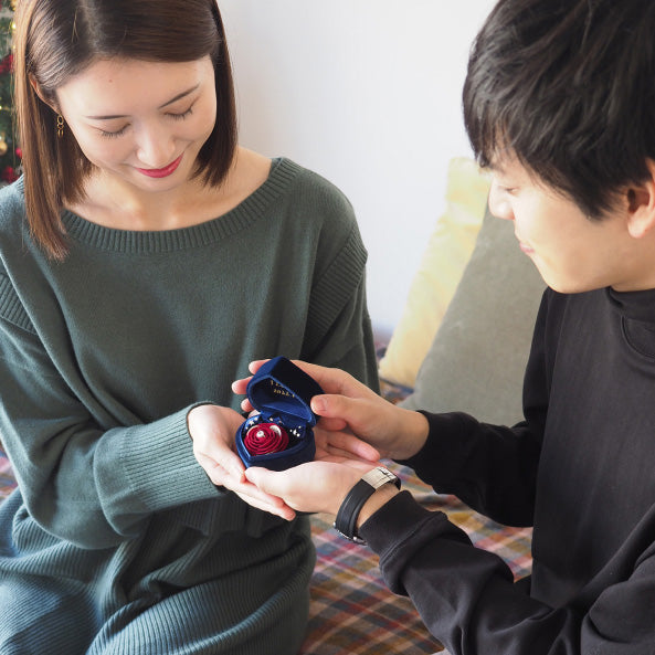 彼女へネイビーのハートボックスを差し出し、赤いバラが咲くプロポーズボックスで箱パカサプライズ。嬉しそうに微笑む彼女の心に残るプロポーズ。