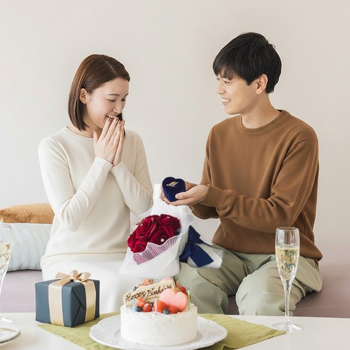 12本の赤いバラの花束をプレゼントした後に、更なるサプライズとして、彼女にプロポーズをする男性。