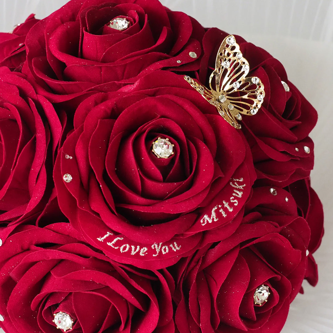 枯れることのないアートフラワー製の、12本の赤いバラの花束。花びらには、メッセージと名前が刺繍できる、特別なギフト。バラには輝くストーン装飾が施されていて、高級感がある。