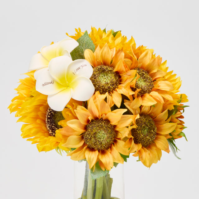 ナチュラルで飾りやすい、ベーシックタイプのひまわりの花束。白いプルメリアに愛のメッセージと名前を刻める、シンプルながら心のこもったフラワーギフト。