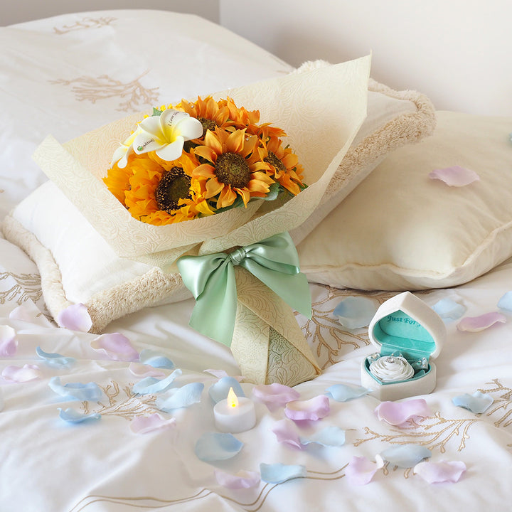 ひまわりの花束とプロポーズボックスを並べたWサプライズ演出。鮮やかな花束と指輪の箱パカで、一生に一度の特別な瞬間を華やかに彩る。