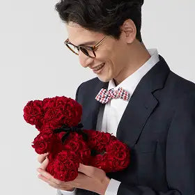 赤バラ製テディベアを抱きかかえる男性