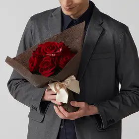 赤バラの花束を手に抱える男性