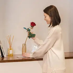 部屋で女性が花瓶にバラを飾っている様子