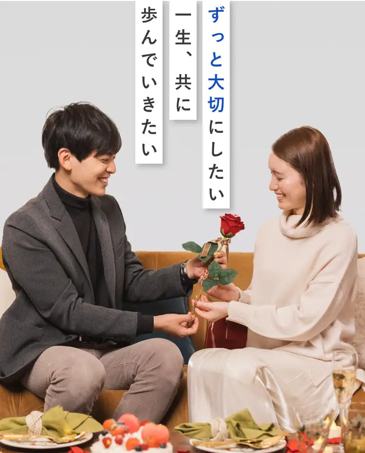 プロポーズに彼女へアートフラワー製の1本の赤いバラをプレゼントする彼と、受け取って喜ぶ彼女。